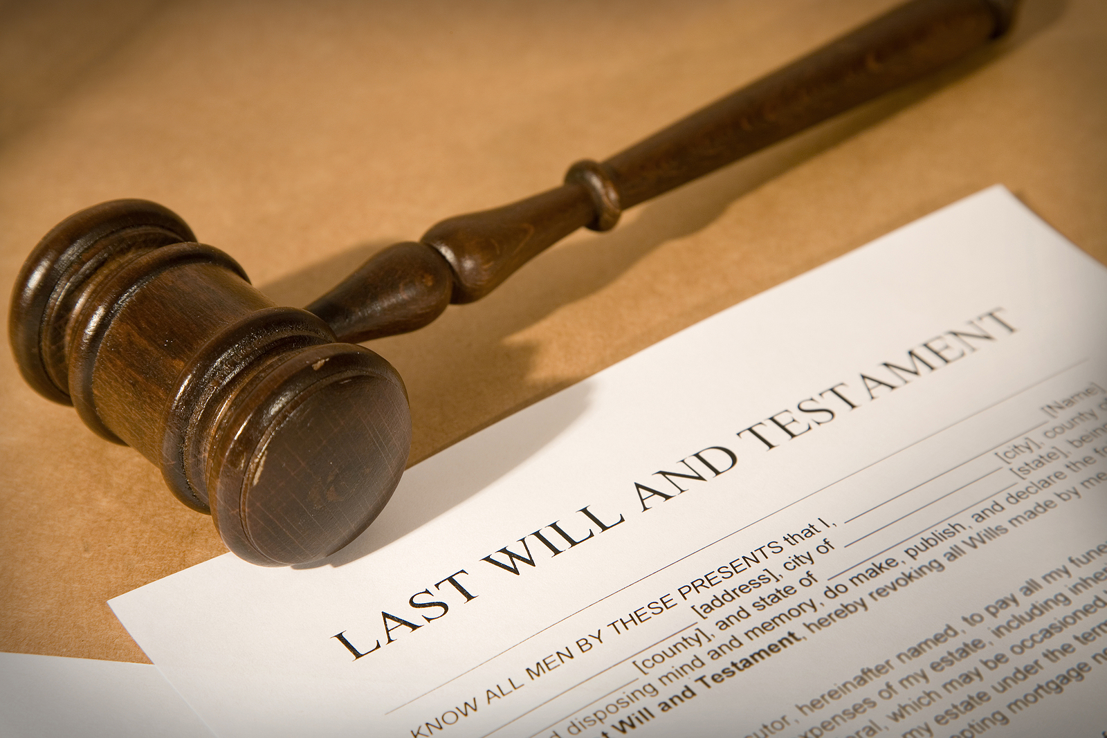 A wooden gavel sitting on top of a document for a last will and testament.
