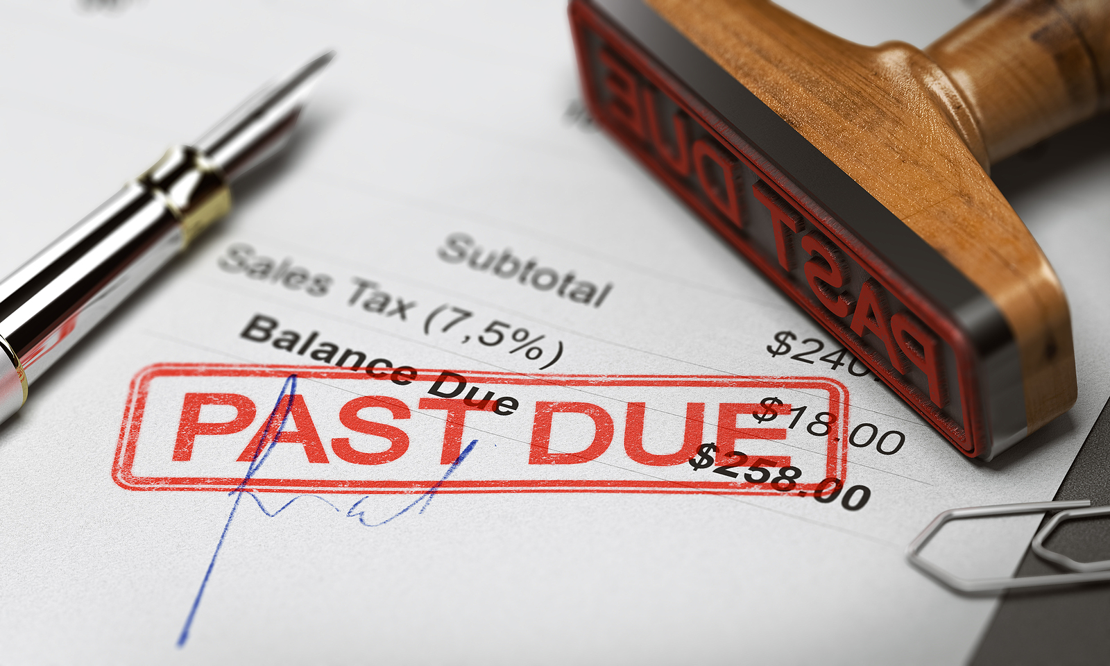 A wooden stamp with the text "past due" and a pen on top of a past due invoice statement.