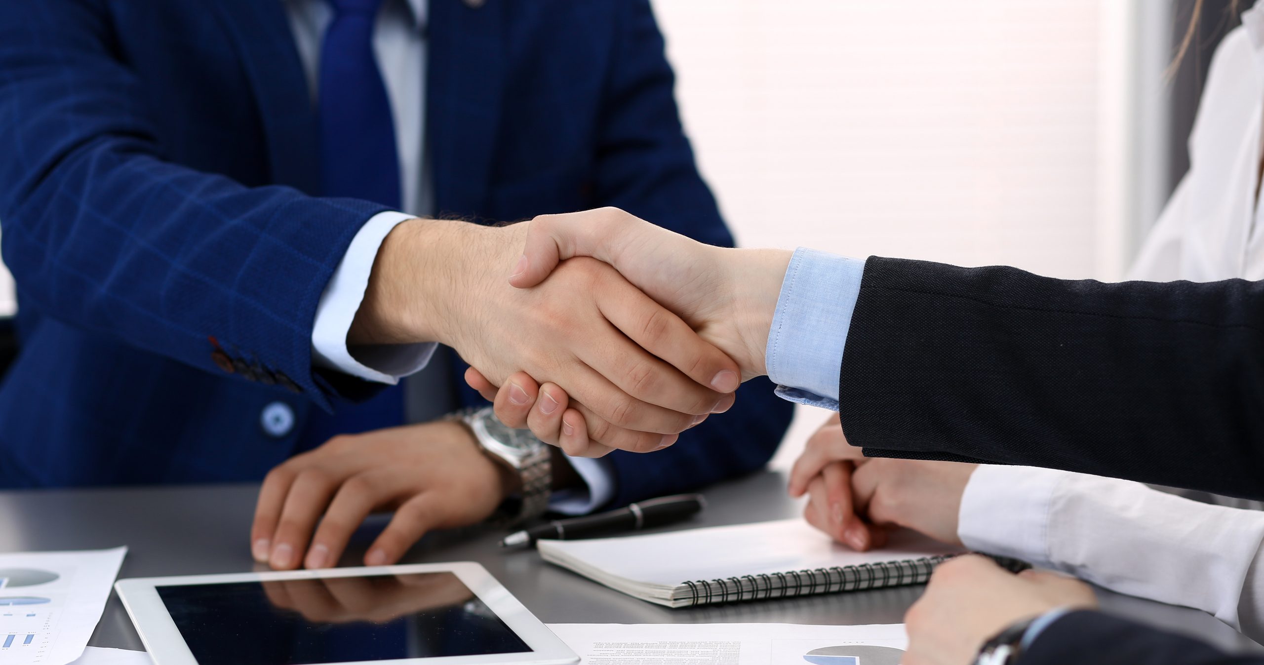 Two business people shaking hands as they finished signing papers, coming to an agreement.