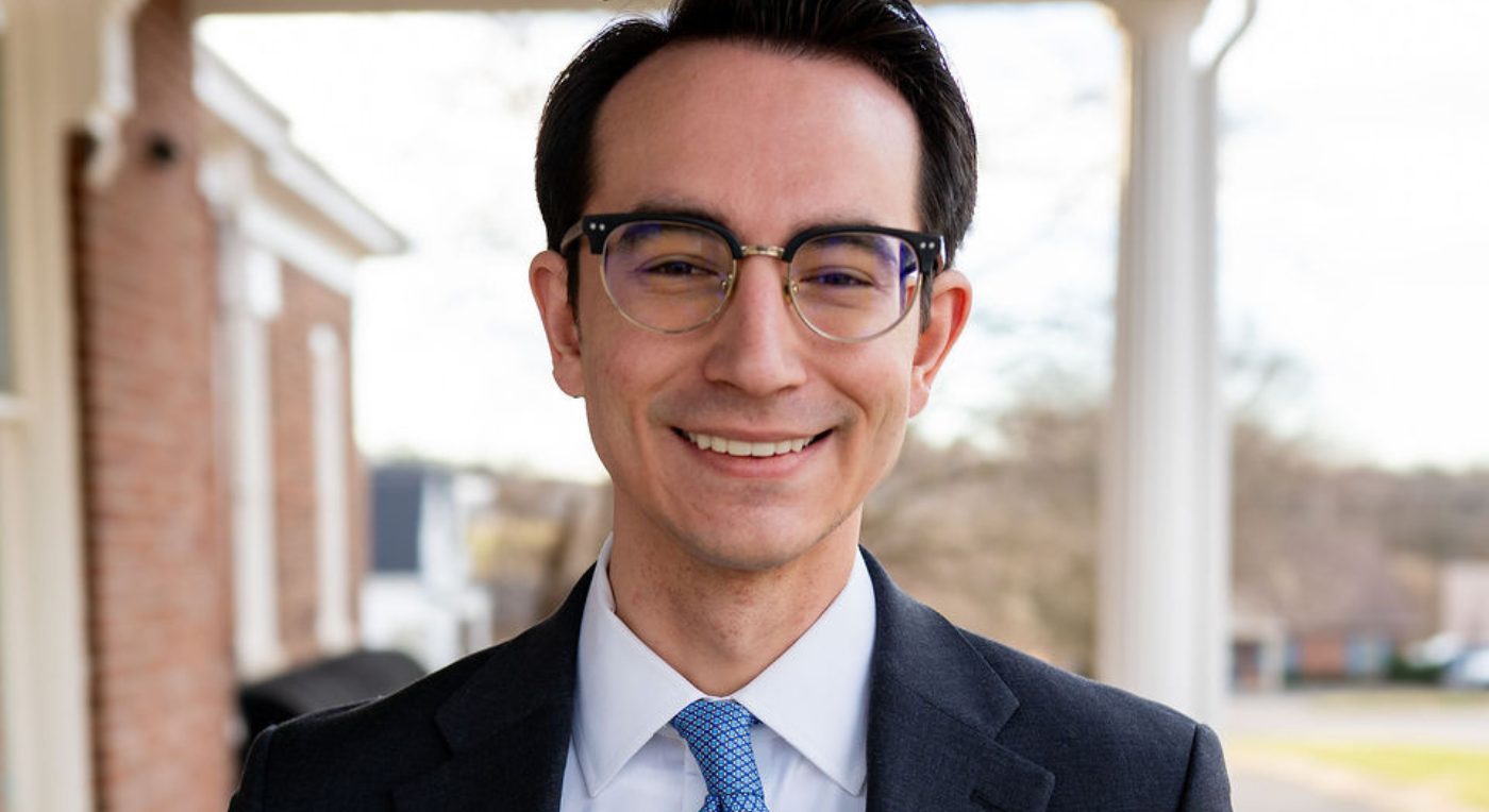 A professional square headshot of attorney Noah Darden smiling in a grey suit, white shirt, and a blue tie.